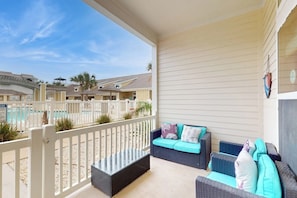 A covered outdoor seating area with wicker furniture and a view of a pool. - Leeward Manor - Heated Pool, Steps to the Beach (Corpus Christi)