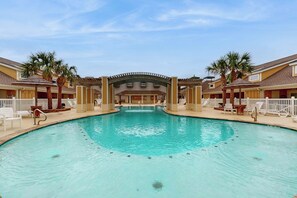 A swimming pool with a central archway, surrounded by lounge chairs and palm trees. - Leeward Manor - Heated Pool, Steps to the Beach (Corpus Christi)
