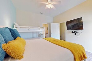 A bedroom with a bunk bed, a television mounted on the wall, and a ceiling fan. - Leeward Manor - Heated Pool, Steps to the Beach (Corpus Christi)