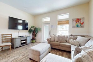 A living room with a flat-screen TV, a sofa, a chair, a coffee table, and a potted plant. - Leeward Manor - Heated Pool, Steps to the Beach (Corpus Christi)