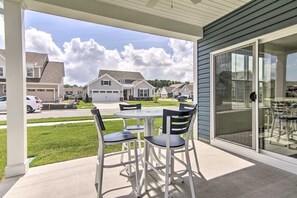A patio with a table and chairs, a sliding glass door, and a view of a residential neighborhood. - Family-Friendly Beach Base with Pool and Shuttle (Ocean View)