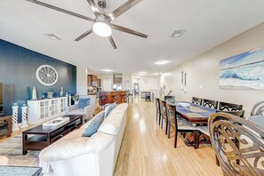 A spacious living area with a dining table and chairs, a ceiling fan, and a view into the kitchen. - Texas Two Steps From Beach (Corpus Christi)