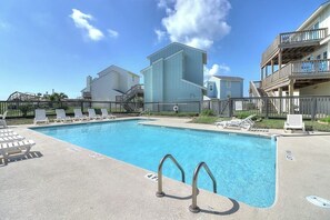 A swimming pool with lounge chairs and a building with a balcony. - Gulf Beach House #10 (Port Aransas)