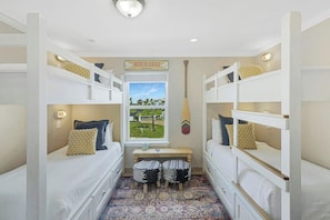 A room with bunk beds, a bench, and a window with a view of a landscape. - Gulf Beach House #10 (Port Aransas)