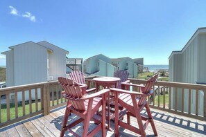 A wooden deck with outdoor furniture and a view of beach houses. - Gulf Beach House #10 (Port Aransas)
