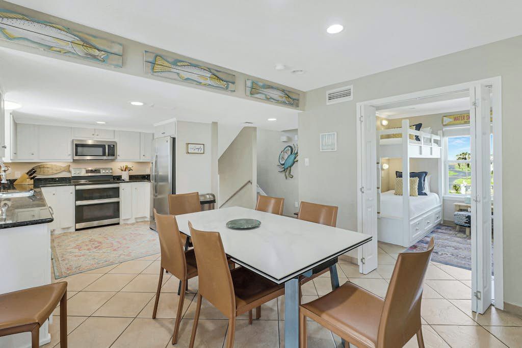 A modern kitchen with white cabinets, a microwave, and a dining area with a table and chairs.