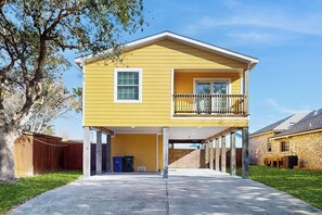 Une maison jaune à deux étages, dotée d’un balcon, d’un garage fermé et d’une cour clôturée.