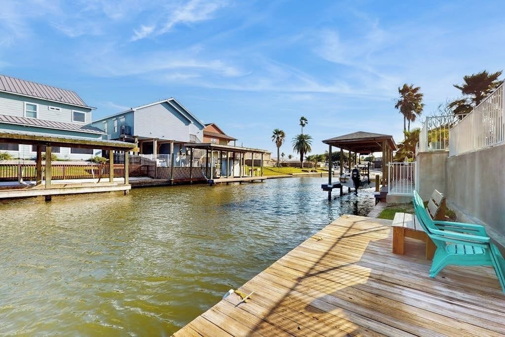A waterfront property with a dock, a covered seating area, and a building with a sloped roof.