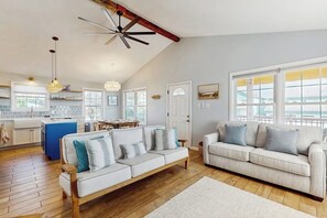 Ein geräumiges Wohnzimmer mit Holzboden, einem weißen Sofa, einer weißen Couch und einem Essbereich mit Tisch und Stühlen.