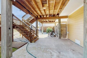 Ein überdachter Außenbereich mit einer Holztreppe, die zu einer Garage führt.
