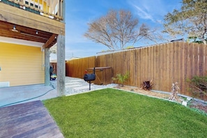 Ein Garten mit Holzzaun, Grill und einer kleinen Gartenanlage.