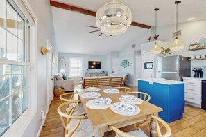 Une cuisine moderne dotée d’un îlot central, d’une table à manger en bois et de luminaires suspendus.