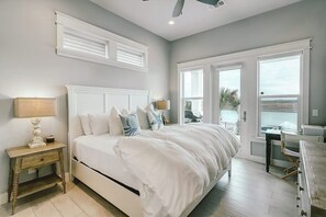 Ein Schlafzimmer mit Bett, Nachttischen, einem Schreibtisch und Blick ins Freie.
