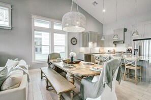 A modern kitchen with a large island, pendant lighting, and a dining area with a bench. - Reserve at St Charles Bay - Cottage By The Sea (Rockport)
