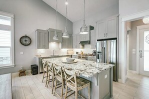 A modern kitchen with a large island, stainless steel appliances, and pendant lighting. - Reserve at St Charles Bay - Cottage By The Sea (Rockport)