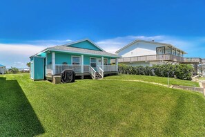 A two-story house with a covered porch and a fenced yard. - The Cottage on Salt Lake (Rockport)