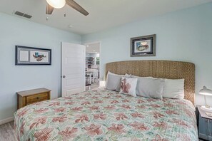 A bedroom with a bed, a nightstand, a door, and a framed picture on the wall. - The Cottage on Salt Lake (Rockport)