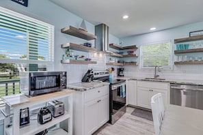 A modern kitchen with white cabinetry, a stainless steel range, and a built-in microwave. - The Cottage on Salt Lake (Rockport)