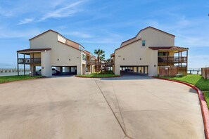 A residential area with two two-story houses, a covered walkway, and a view of the ocean. - Baydreaming - Bay Views, Pool & Boat Slip (Rockport)
