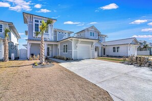 A residential area with multiple houses, a driveway, and a clear sky. - Palm Breeze at the Reserve (Rockport)