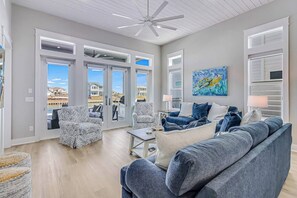 A spacious living room with a large gray sofa, patterned armchairs, and a coffee table. - Palm Breeze at the Reserve (Rockport)