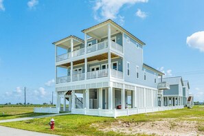 Ein zweistöckiges Strandhaus mit Balkon, einer überdachten Veranda und einem Hydranten im Vordergrund.
