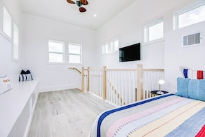 Ein Schlafzimmer mit einem Bett, einem Fernseher an der Wand und einer Treppe.