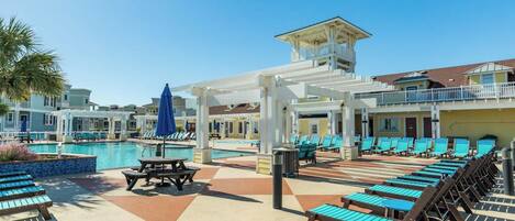 A poolside area with lounge chairs, a table, and umbrellas.