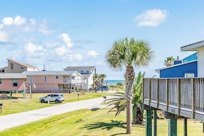 A coastal residential area with houses, a clear sky, and a palm tree. - The Treehouse - Steps to the Beach & Sunny Deck (Galveston)