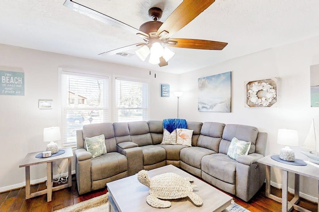 Sala de estar com sofá seccional, ventilador de teto e decoração com tema de tartaruga.