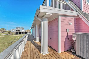 A pink building with a wooden deck and white railings. - Pink Lady by the Sea (Galveston)