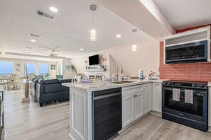 Cocina moderna con una isla grande, horno integrado y televisor de pantalla plana.