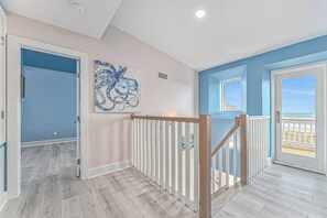 Ein Flur mit Holzboden, einer blauen Wand und einer Tür, die auf einen Balkon mit Aussicht führt.