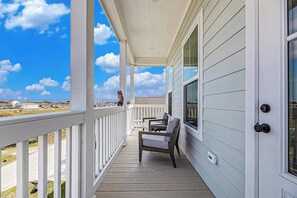 Eine überdachte Veranda mit Geländer, zwei Stühlen und Blick auf die Landschaft.