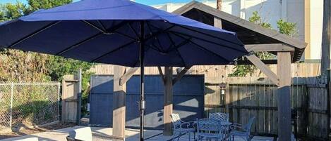 A patio area with outdoor furniture, including chairs and a table, under a large umbrella.