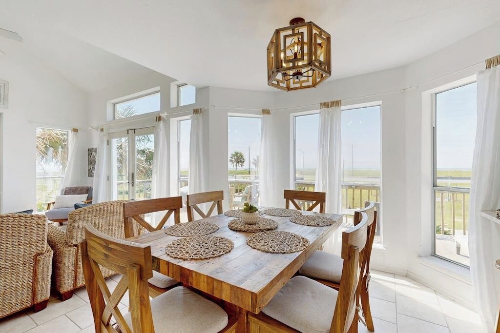 Un vaste espace dédié à la salle  à manger, avec une table et des chaises en bois, de grandes fenêtres et une vue sur l’extérieur.