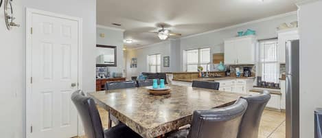 A spacious kitchen with a granite countertop, white cabinets, and a dining area with a marble table and leather chairs.