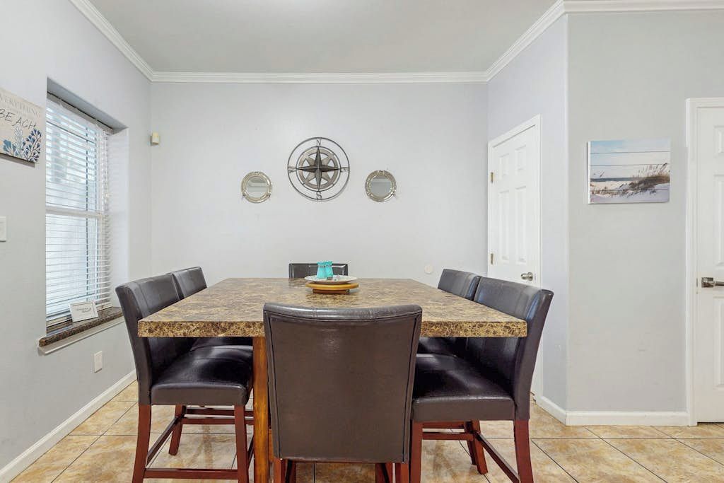 A dining area with a rectangular table, six chairs, and a decorative wall piece.