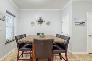 A dining area with a rectangular table, six chairs, and a decorative wall piece. - Pura Vida Unit A - Private Pool, Sleeps 13 (South Padre Island)