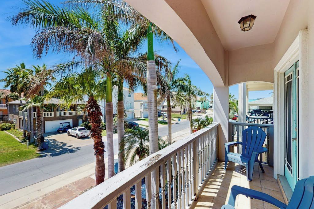 A balcony with a view of palm trees and a street.