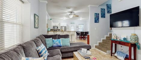 A living room with a sectional sofa, a coffee table, and a flat-screen TV.