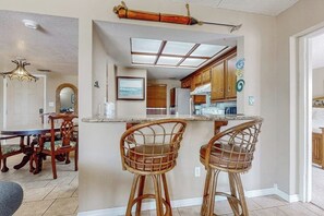 A kitchen with a bar area, wooden chairs, and a dining table with chairs. - Marlin Arms Condominiums #9 (South Padre Island)