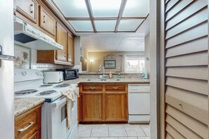 A kitchen with wooden cabinets, a stove, a microwave, and a dishwasher. - Marlin Arms Condominiums #9 (South Padre Island)