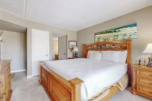 A bedroom with a wooden bed, a nightstand, a dresser, and a painting on the wall. - Marlin Arms Condominiums #9 (South Padre Island)