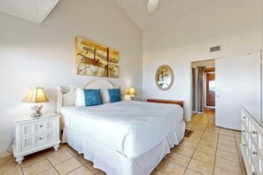 A bedroom with a bed, bedside tables, a mirror, and artwork on the wall. - Suntide II Condominiums #507 (South Padre Island)
