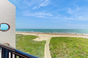 A beach view from a balcony with a clear sky and a sandy path leading to the shore. - Suntide II Condominiums #507 (South Padre Island)
