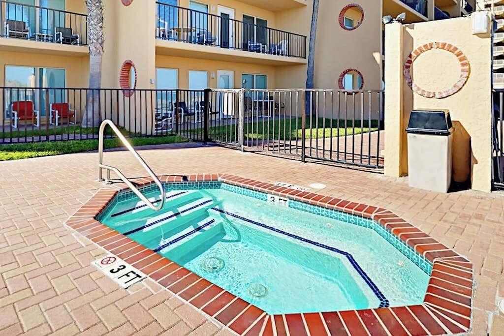A swimming pool with a 3 FT depth marker, surrounded by a brick deck and a metal fence.
