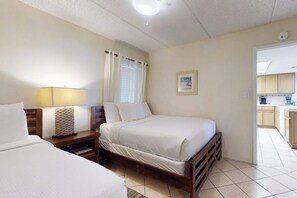A bedroom with a bed, bedside tables, a lamp, and a window with curtains. - Suntide II Condominiums #207 (South Padre Island)