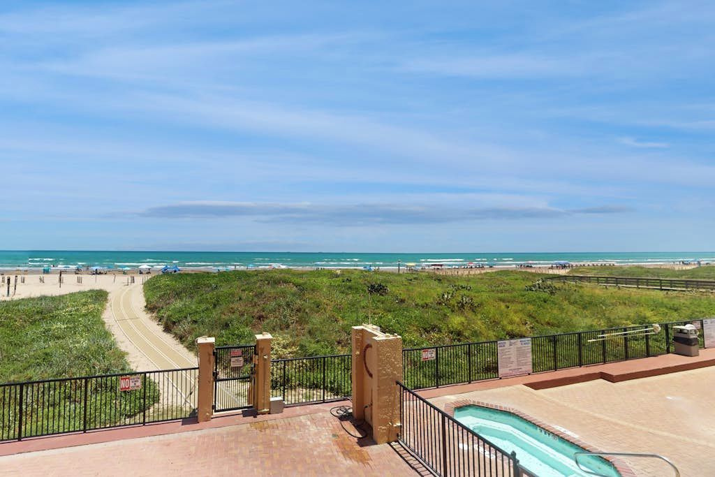A pool area with a view of the beach and ocean.