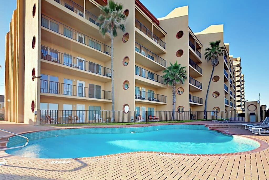 Ein Hotel mit Schwimmbad, mehreren Balkonen und Palmen.
